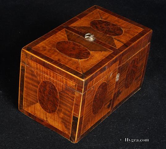 Hygra.com: Tea Chest circa 1780. The top has a central Dutch brass handle. Although the pattern is the same as the front, there is an additional subtle design adjustment, which adds a pleasing extra visual treat. The central half diamond shapes are quite a lot darker than the other three on each side, giving the eye a pleasant surprise without compromising the symmetry. This is a box of great complexity and yet without any hint of over decoration. A truly neoclassical chest made by a master. Enlarge Picture